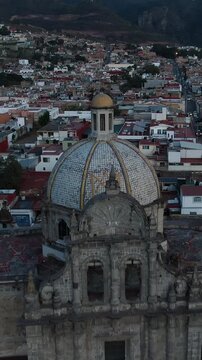 Pullback vertical aerial over the El Sagrario Parish church facade and historic city center of Ciudad Guzman (Zapotl&aacute;n el Grande), Jalisco, Mexico at dusk