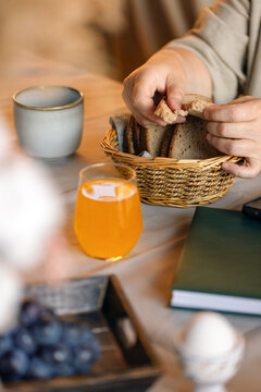 Woman in outdoors gazebo slowly eats breakfast alone. A wicker basket of rye bread on a wooden table. Slow breakfast concept