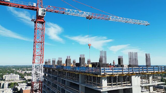 Construction site with tower crane beside unfinished high-rise building