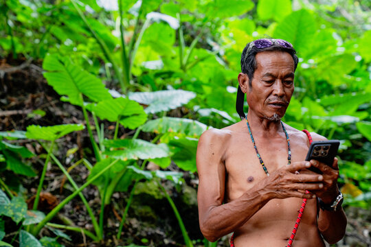 Indigenous man using smartphone in lush tropical forest