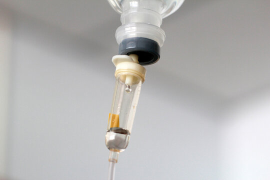 Macro close up of an intravenous drip chamber with saline solution in a hospital.