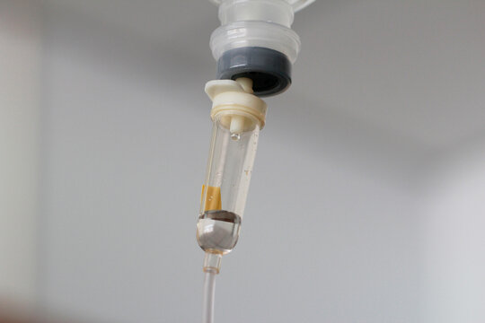 Macro close up of an intravenous drip chamber with saline solution in a hospital.