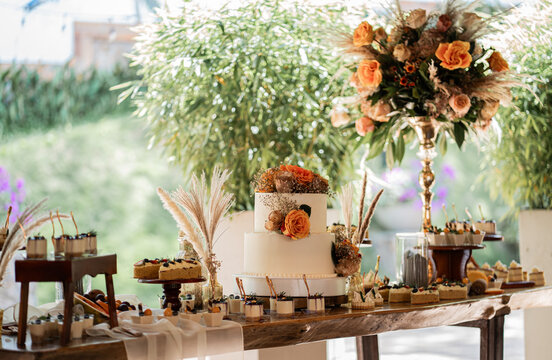 Mesa de postres con pastel de boda y arreglos florales en elegante recepci&oacute;n de matrimonio