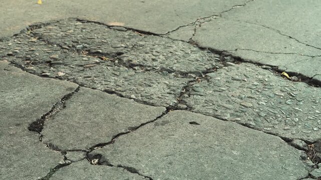 Cracked asphalt pavement with rough patches and damaged road surface