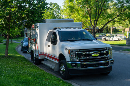 White Ford F-Series Super Duty service truck with red stripes and '102' emblem, featuring warning lights, parked on a quiet residential street, symbolizing emergency, utility.