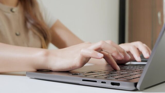 Close up of a person's hand is working using laptop to type report or document.