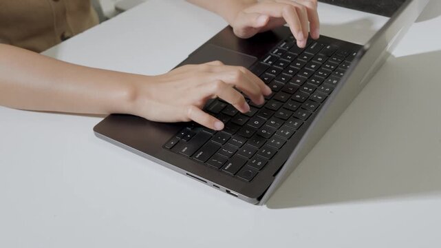 Close up of a person's hand is working using laptop to type report or document.