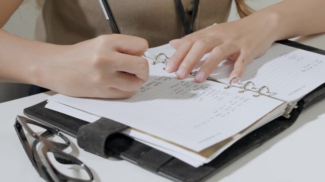 Close up of a person working and writing report or note in a book.