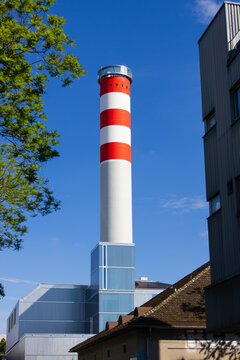Red and white industrial chimney standing under blue sky in Zurich Switzerland