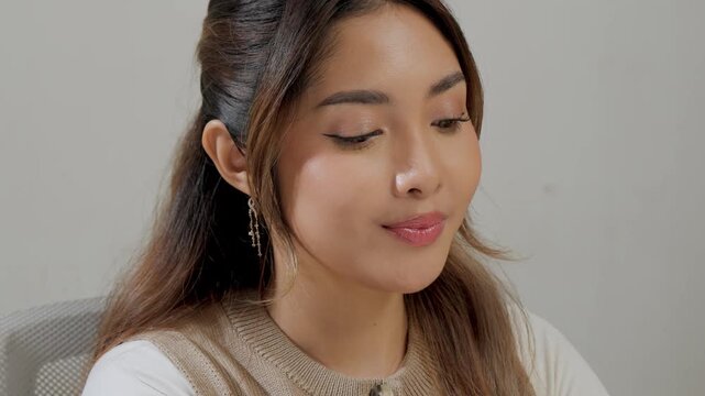 Close up of a young Asian woman's face working and typing on her laptop.