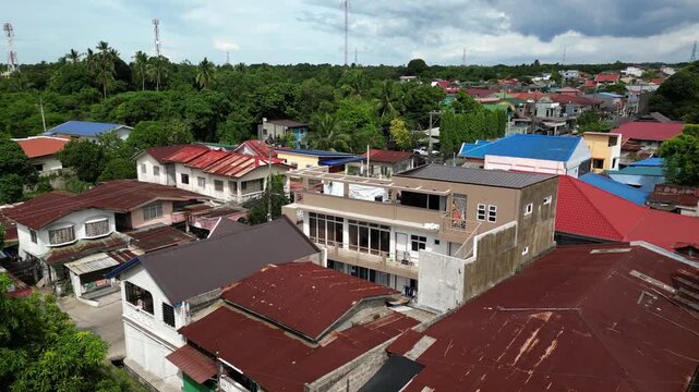 Atmospheric drone footage of CJDC Building and the surrounding Alfonso Cavite town center showcasing mixed commercial buildings and a calm provincial roadside environment.