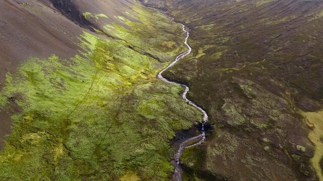 River flow through volcanic Icelandic mountain valley, aerial view