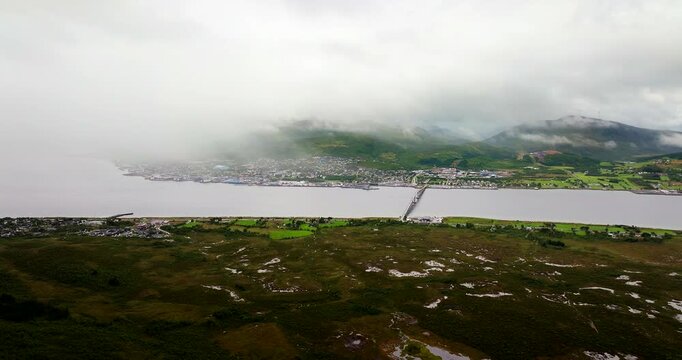 Drone view of coastal town and bridge partially obscured by low cloud and fog in Sortland, Norway. Aerial, copy space