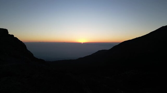 Drone footage capturing a sunrise moment at Mount Papandayan, West Java, Indonesia. Clear cloudless sky with a blue-to-orange gradient stretching across the horizon.