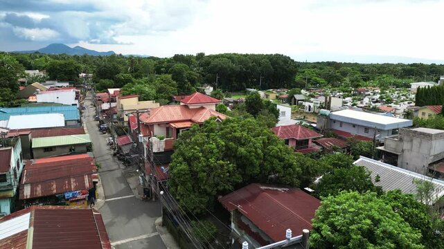 Slow pan drone footage across Rizal Mabini Burgos Road in Alfonso Cavite Philippines featuring residential homes, green trees, and local roads in a calm provincial environment.