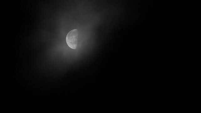 Tokyo, Japan - July 7, 2026: Half moon covered with moving clouds at dawn