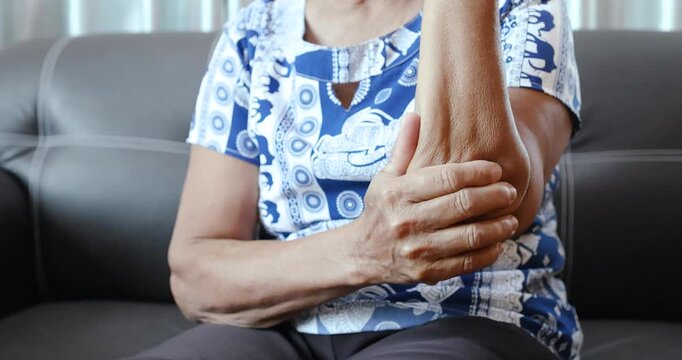 Senior massaging a painful arm near the elbow, arm pain, muscle soreness, joint inflammation, rehabilitation, healthcare, medical treatment, and aging concept. close-up