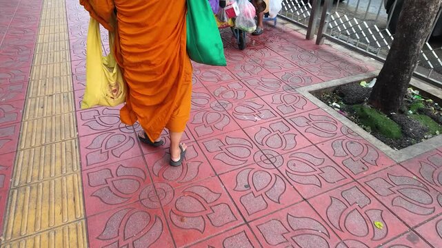 Buddhist Monk in Orange Robe Walking on Bangkok Sidewalk