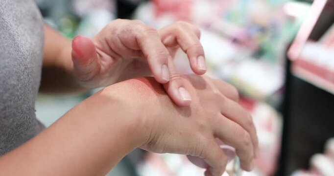 Woman testing a cosmetic product on the back of her hand in a beauty store. Skincare, makeup, beauty shopping, product texture, and consumer choice, close-up