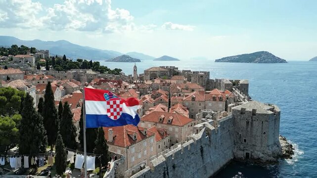 Aerial view of dubrovnik old town with croatian flag waving over historic city walls and adriatic sea coastline