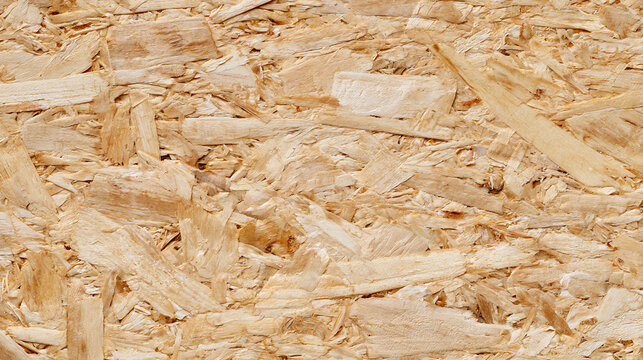 Close-up image captures the textured surface of wood-based panel, a composite building material, showcasing its natural wood chip construction and light tan color