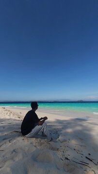Man Sitting on Beach Looking at Ocean