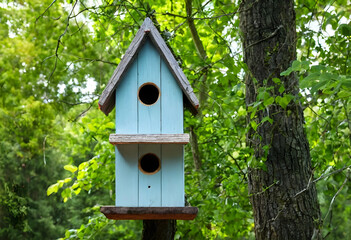 Fototapeta premium Blue wooden bird house on tree in green forest