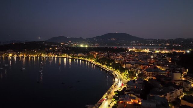Corfu Town Night Aerial View, Garitsa Bay Coastline with City Lights and Sea Reflections, Greece Drone Footage