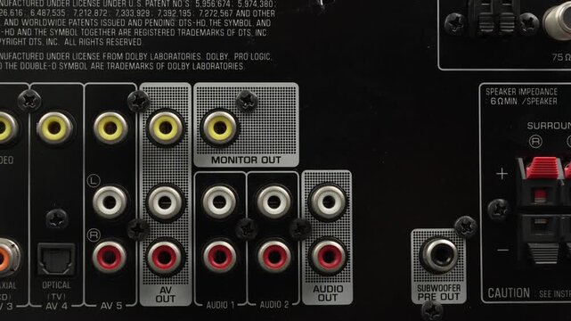 Static macro shot of color coded RCA, component, coaxial and optical ports on the back of a home theater AV unit.