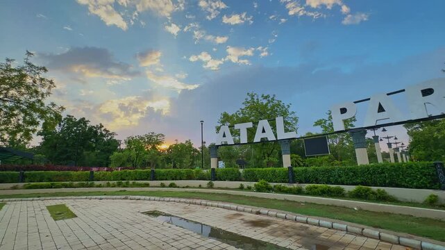 Smooth panning shot of the iconic Atal Park entrance in Rewa during golden hour, featuring landscaped gardens, dramatic evening sky, and modern urban park architecture.