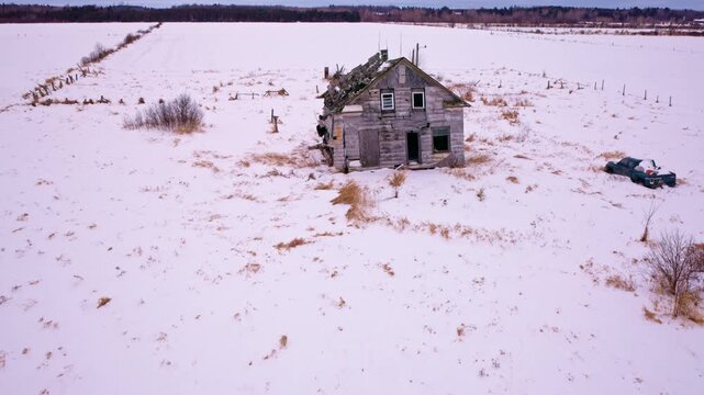 Drone footage capturing a snow-covered countryside with a worn-down historic barn.