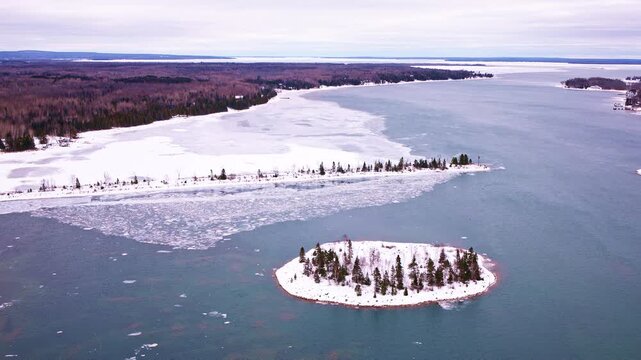 Overhead drone footage of a partially frozen Lake Superior bay bordered by an untouched winter landscape.