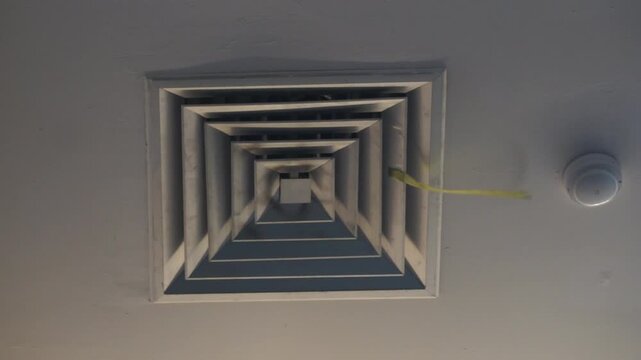 Footage of Square ceiling AC diffuser vent on a white wall, low angle close up view of commercial central air conditioning ventilation system, interior building maintenance and hvac concept.
