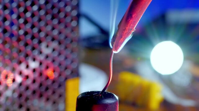Closeup of Soldering Iron Tip Melting Solder Wire on Workshop Background. Electric Repair Process Emits Smoke from Flux Component. Engineering Maintenance Service of Hardware Microchip 4k