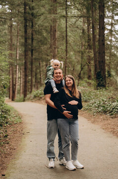 A warm family walk along a forest path. Parents are spending time with their child amidst tall trees and nature.