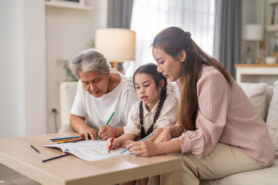 Asian multi generational family of grandmother mother and little girl drawing together at home, Child creativity, family bonding, happy quality time, educational development and lifestyle activity