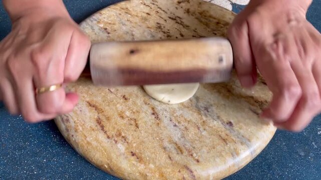 Rolling a dough of whole wheat flour into circles to make a tea time snack called mathri or matthi