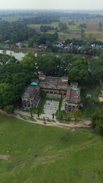 Aerial drone view of an ancient abandoned palace ruins surrounded by lush green trees and a