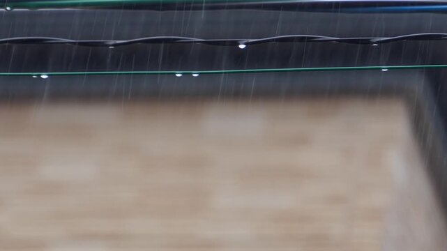激しい雨の中で次から次へと電線から滴り落ちる水滴のスローモーション