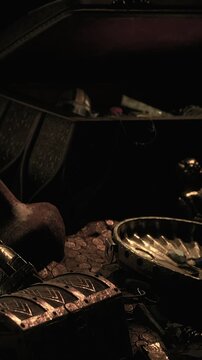 A treasure chest sits open with coins scattered around it. Old artifacts and trinkets are visible in the dim light. The scene suggests a hidden treasure discovery.