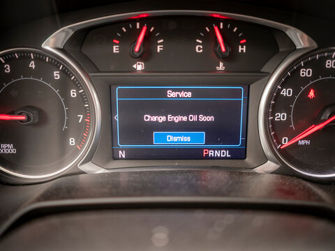 A vehicle digital dashboard screen displaying a Change Engine Oil Soon service alert message between standard fuel temperature and speed gauges