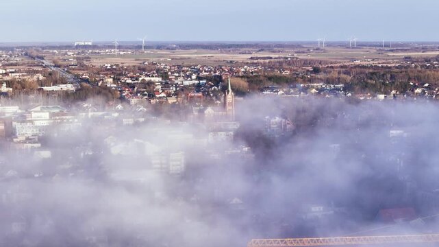 Misty fog covers Palanga city buildings during colorful sunset view.