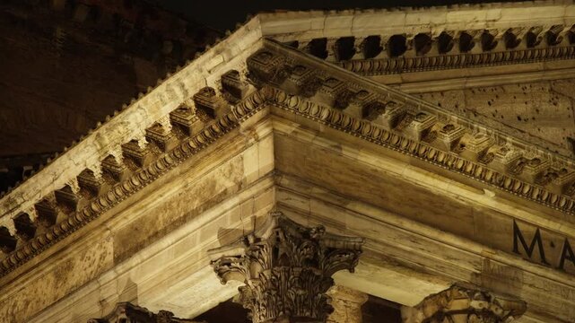 Architectural close-up of the pantheon's corinthian capitals and pediment illuminated at night. Majestic roman temple in rome, italy
