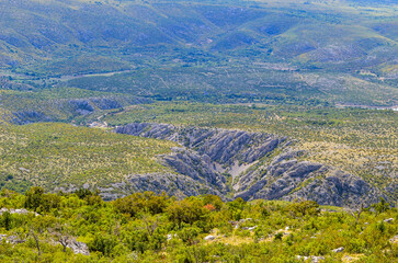 Dramatic Krupa Canyon cuts through the rugged karst landscape of northern Dalmatia, revealing striking limestone cliffs and a winding river below. This is a scenic Croatian travel destination. © Den