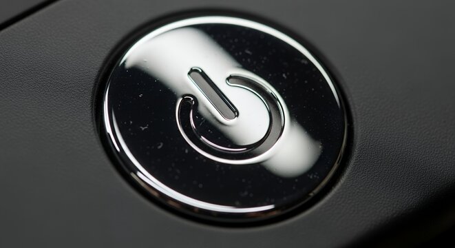 Close up of a shiny power button on a dark surface.