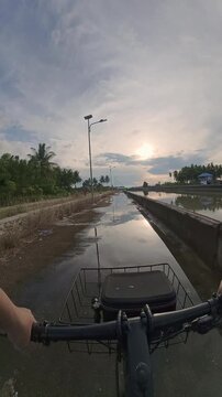First-Person View of Biking by a Canal at Sunset