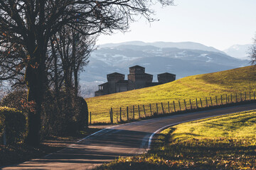 medieval castle in italy with green fields and sowy mountains and a road in the foreground © Francesca Emer