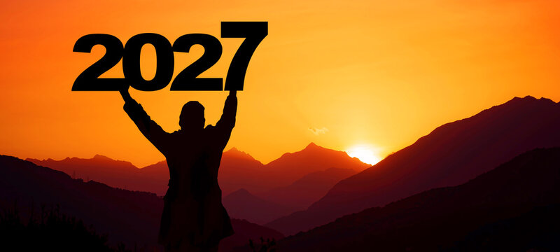 Landscape background banner panorama 2027 - Breathtaking view with black silhouette of mountains and man holding year, in the morning during the sunrise