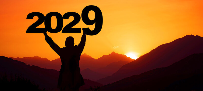 Landscape background banner panorama 2029 - Breathtaking view with black silhouette of mountains and man holding year, in the morning during the sunrise