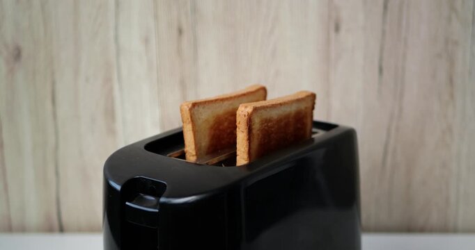 Burnt toast popping up from toaster in kitchen during breakfast preparation. Vertical video captures cooking mistake, kitchen mishap, food waste and everyday household routine at home.